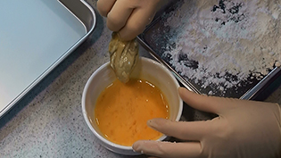 牡蠣を卵液にくぐらせ、余分な卵液はボウルの縁でぬぐう