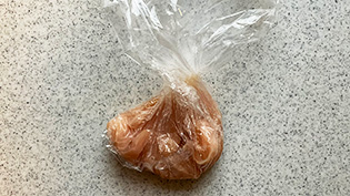 ポリ袋に鶏肉と塩と酒を入れ、軽く揉み込んでいる