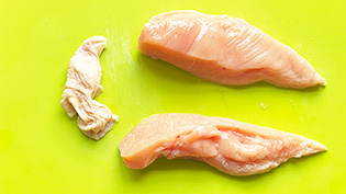 鶏肉の皮をはぎ、縦半分に切っている