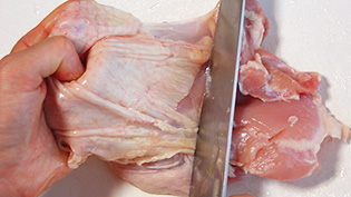 鶏肉の皮をはいで、一口大に切っている