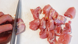 皮をはいだ鶏肉を一口大に切っている