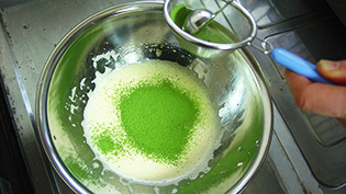 抹茶を茶こし器でふるいながら加えている