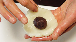 生地にあんこをのせて包んでいるところ