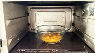 耐熱ボウルに冷凍マンゴー、砂糖、レモン果汁を入れ、電子レンジ(600W)で1分間加熱している
