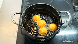 揚げ油を170℃に熱し、チーズボールを転がしながらこんがりするまで約3分揚げている