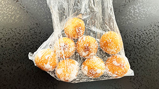 温かいうちに、耐熱のビニール袋に砂糖大さじ1とチーズボールを入れ、シャカシャカとふり混ぜ、砂糖をまぶしている