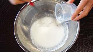 白玉粉をボウルに入れ、水を少しずつ加えて泡立て器で混ぜている