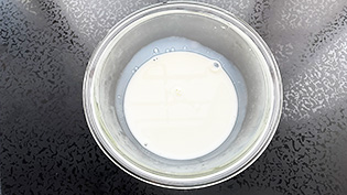 砂糖大さじ4と牛乳100mlを耐熱容器に入れ、電子レンジ500Wで1分温めて砂糖を溶かしている