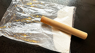 ビニール袋に白玉粉を入れ、麺棒で粉を細かく潰している