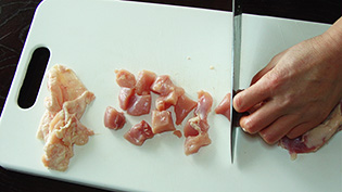 鶏肉の皮をはいで食べやすい大きさに切っている