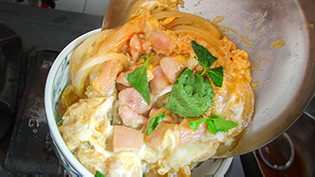 鍋を傾けながらご飯の上に盛っている