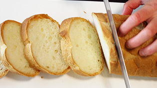 フランスパンを斜め1cm幅に切っている