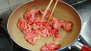 フライパンにごま油を熱し、2の豚肉を入れて炒めている