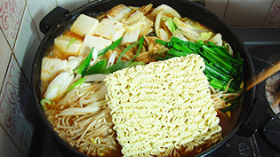 鍋にラーメンやお餅を入れている