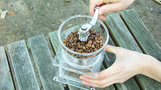 コーヒー豆を手動のミルで挽いている