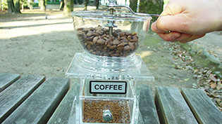 手動のミルでコーヒー豆を挽いている