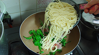 ゆであがったスパゲティを加えている