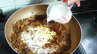 中火にして生クリームと牛乳を加えている