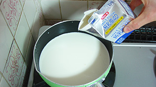 牛乳と生クリームを鍋に入れ、中火にかけている