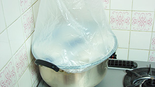 天板にレジ袋をかぶせ、熱めのお湯をはった鍋に乗せ、蒸気で温めている様子