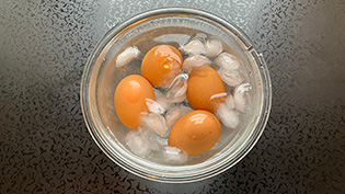 鍋から卵を取り出し、氷水に入れてすぐに冷やしている