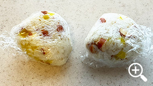 ラップで包んで三角形に握ったいぶりがっこ風おにぎり