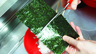 海苔をハサミで一枚を4等分に切っている