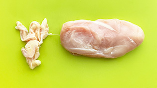 鶏むね肉の皮をはいでいる