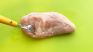 肉が柔らかくなるように、フォークで肉を刺している