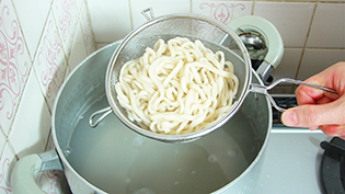 ゆで上がった麺をザルで引きあげ、水気を切る