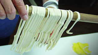 余分な打ち粉をはらいながら麺をふるう