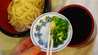 ねぎと生姜の薬味を温めた麺つゆに入れる