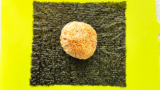 ラップを取り除き、焼き海苔の上にのせて包んでいる