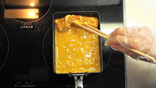 卵焼きを箸で持ち上げて、下の部分にも卵液を流し込む