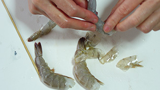 エビの背ワタを取り、尾の一節を残して殻をむいている