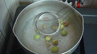 網じゃくしで転がしながら茹で、薄皮をむいている