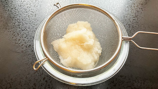 カブの皮を厚めにむいてすりおろし、ザルで水気を切っている
