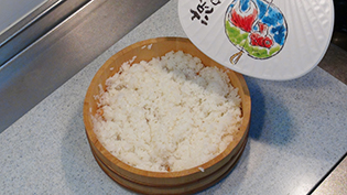 すし飯を飯台に広げて、うちわであおいで急速に冷ましている