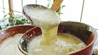 炊き上がった麦ごはんをお茶碗によそい、とろろ汁をかけている