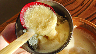 炊き上がった麦ごはんをお茶碗によそい、とろろ汁をかけている