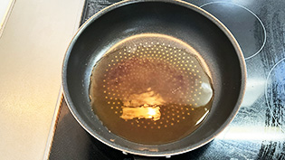 フライパンに煮汁と塩ひとつまみを入れて強火にかけている