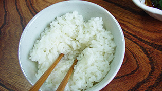 ご飯を茶碗に盛り、箸でくぼみをつけている