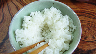 ご飯を茶碗に盛り、箸でくぼみをつけている