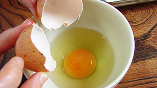 お茶碗に先に卵を入れて割りほぐしている