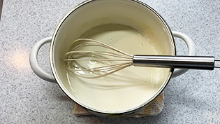 1/5量の牛乳をルウに入れ、泡だて器でかき混ぜている