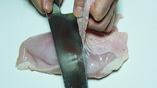 鶏むね肉の皮をはいでいる