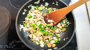 フライパンにサラダ油(炒め用)を熱し、玉ねぎ、鶏肉、ピーマン、マッシュルームの順に炒めているところ